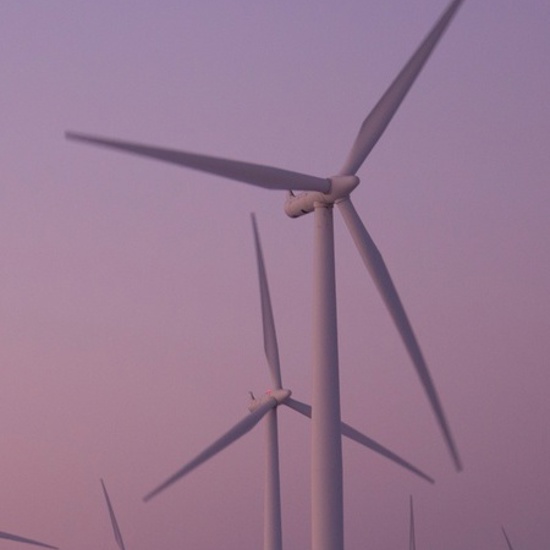 Vindkraftverk mot rosa himmel.